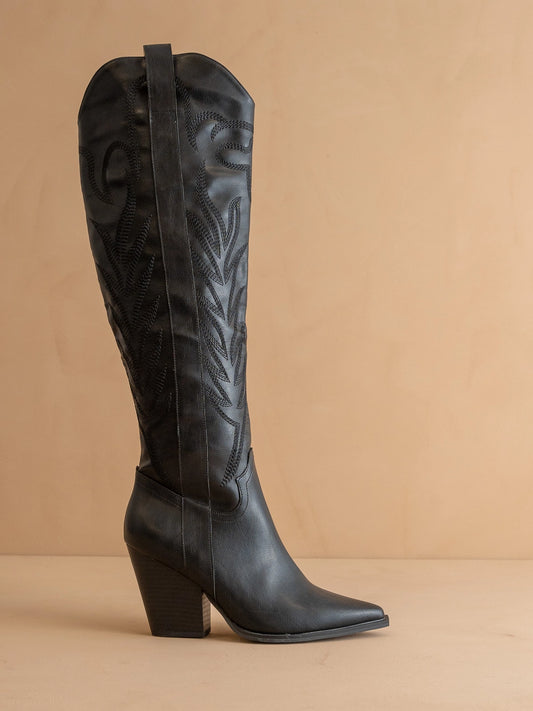 Black knee-high western boot with a block heel on a beige background
