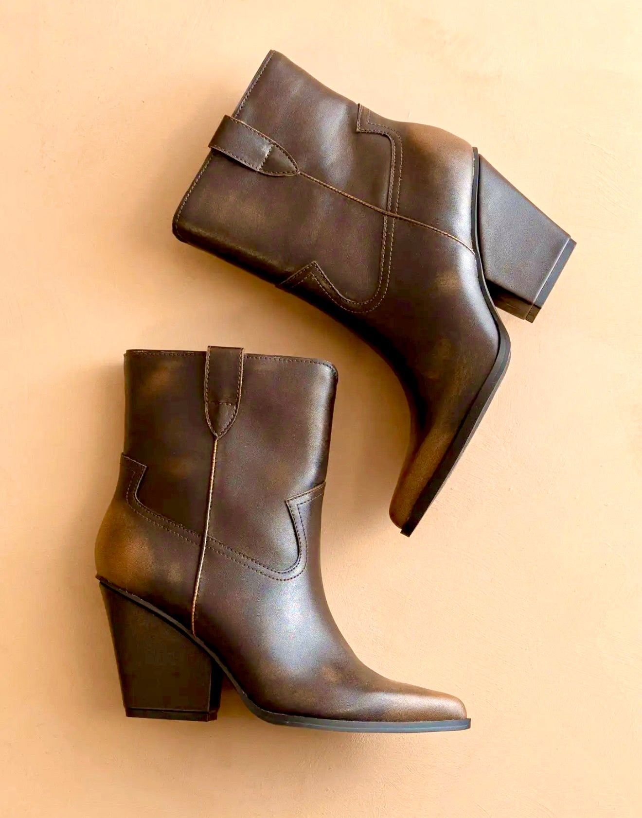 Pair of brown two toned distressed  leather ankle boots on a beige background