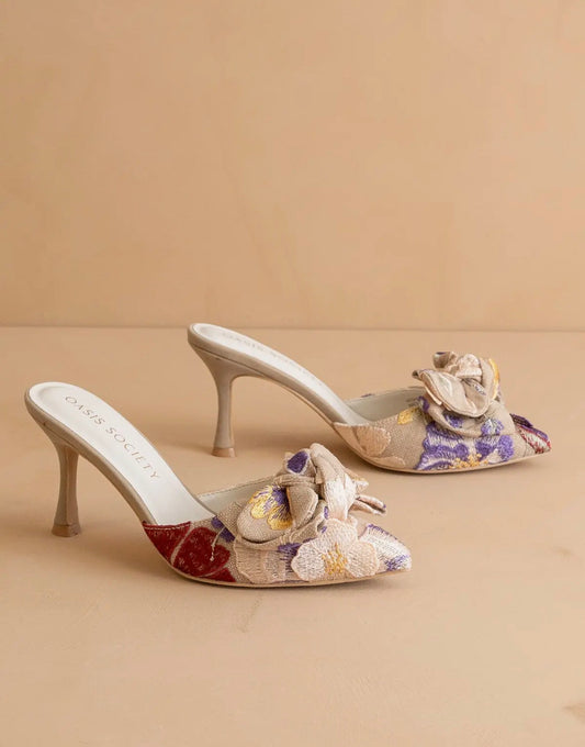 Pair of floral tapestry high-heeled  slip on shoes on a beige background