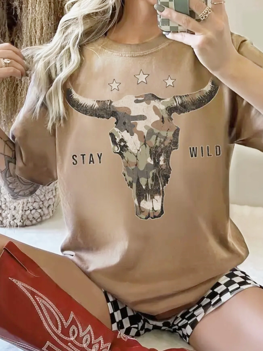 Person wearing a mineral taupe t-shirt with a camouflage longhorn bull skull design and 'Stay Wild' text.