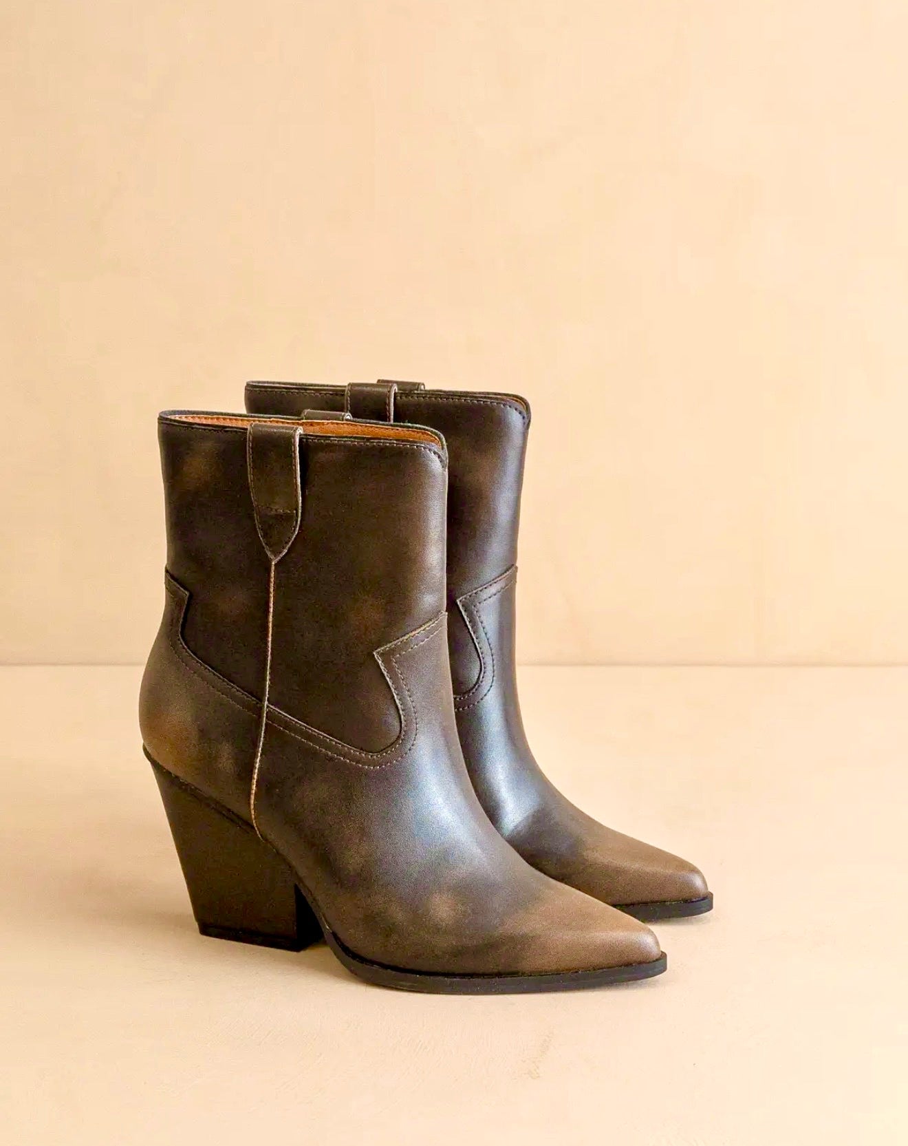 Pair of two toned distressed style brown leather ankle boots on a beige background