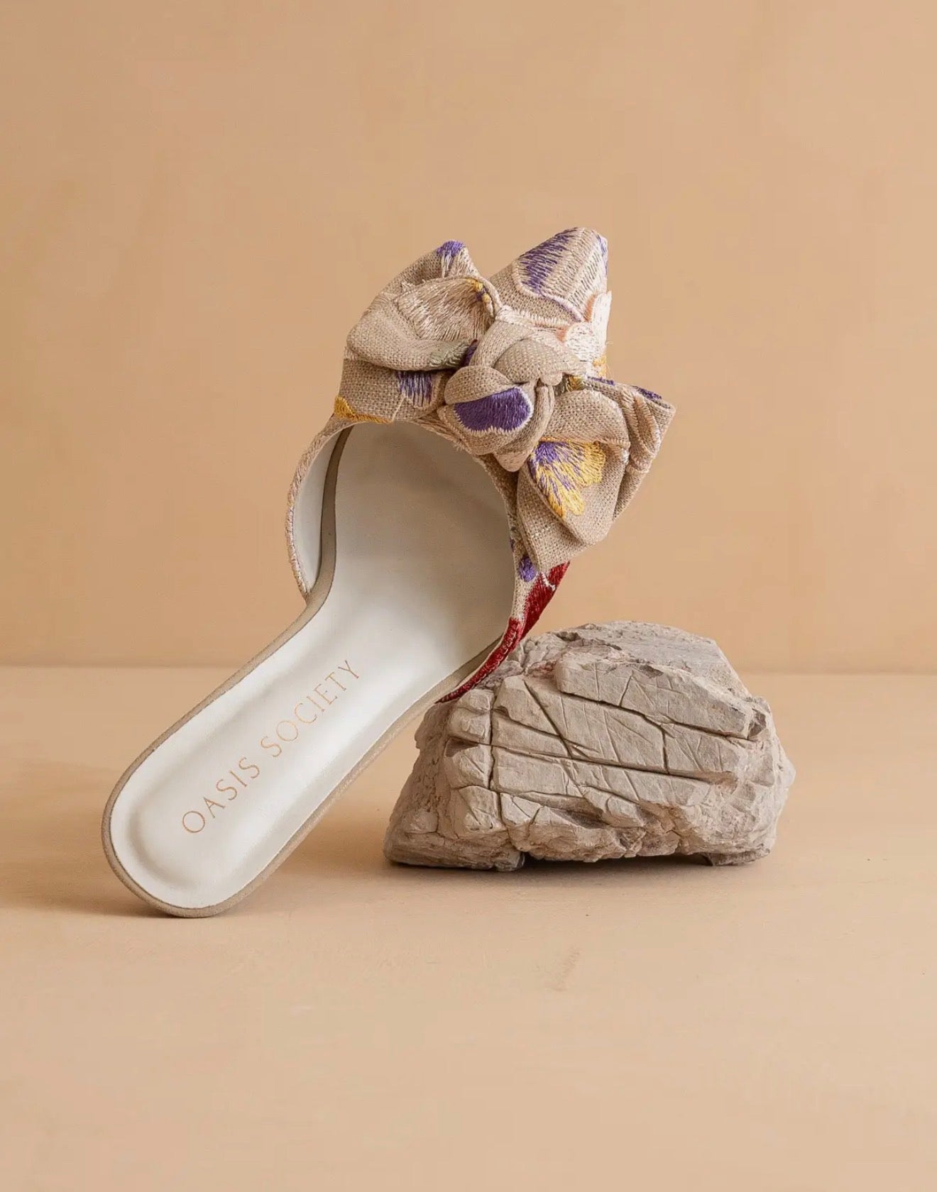 Decorative slip on high heel sandal with floral  tapestry design with bow accent on a beige background