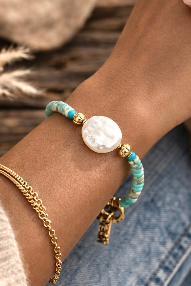 Bracelet with African turquoise (Jasper) beads and a white coin pearl on a wrist against a blurred background