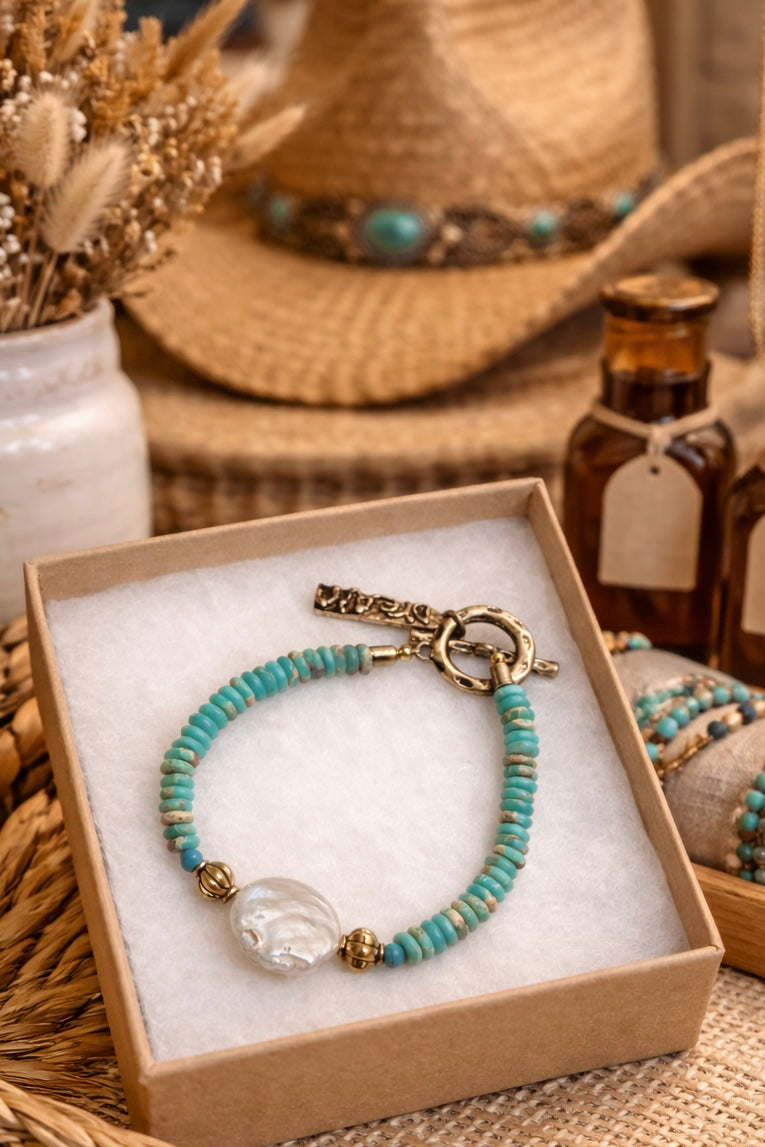African Turquoise (Jasper) beaded bracelet with large coin pearl and a charm in a box, surrounded by rustic decor.