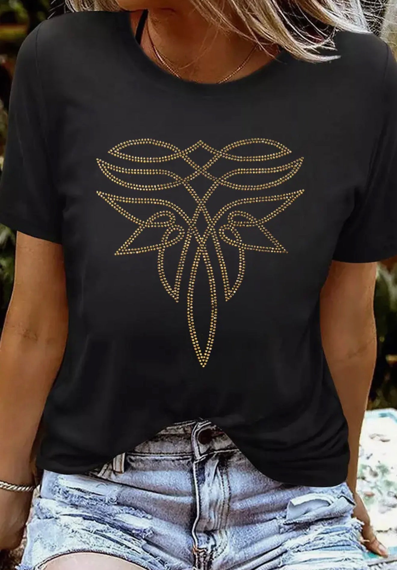 Person wearing a black t-shirt with a boot stitch rhinestone bling design.