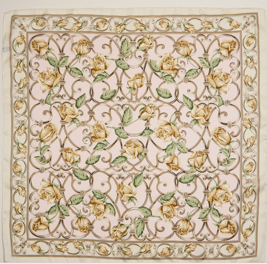 Decorative design on a silky scarf with yellow roses and green leaves on a beige background
