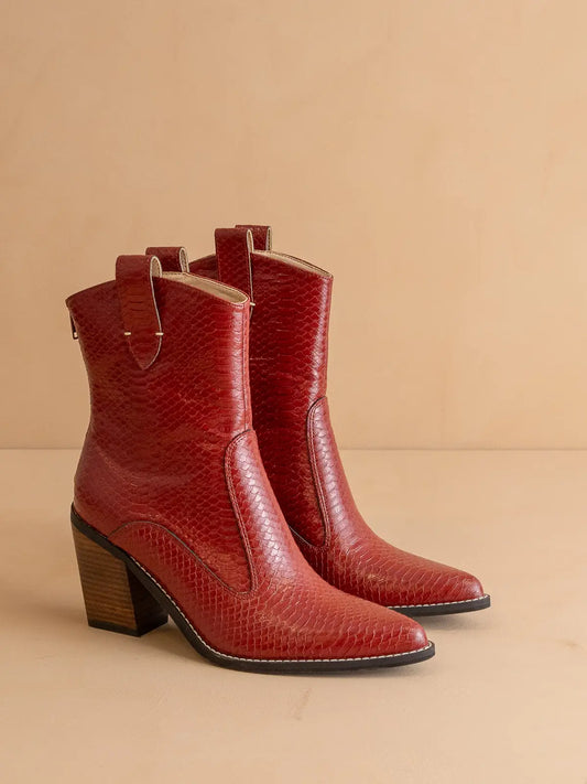 Red leather snake skin embossed ankle boots with a block stacked heel on a beige background