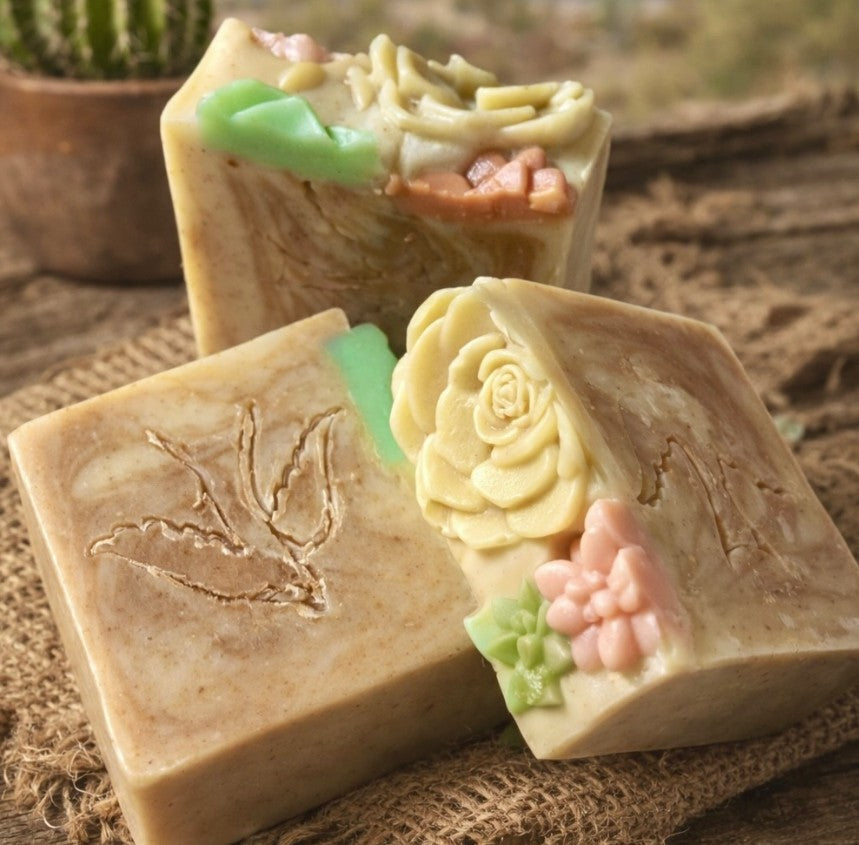 Handmade soap bars with floral succulent designs on a textured surface